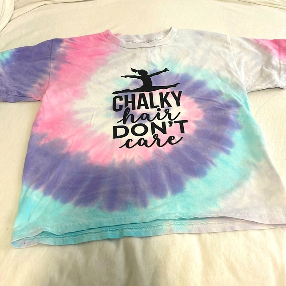 Tie-dye shirt, black lettering that says chalky hair don’t care with a gymnast